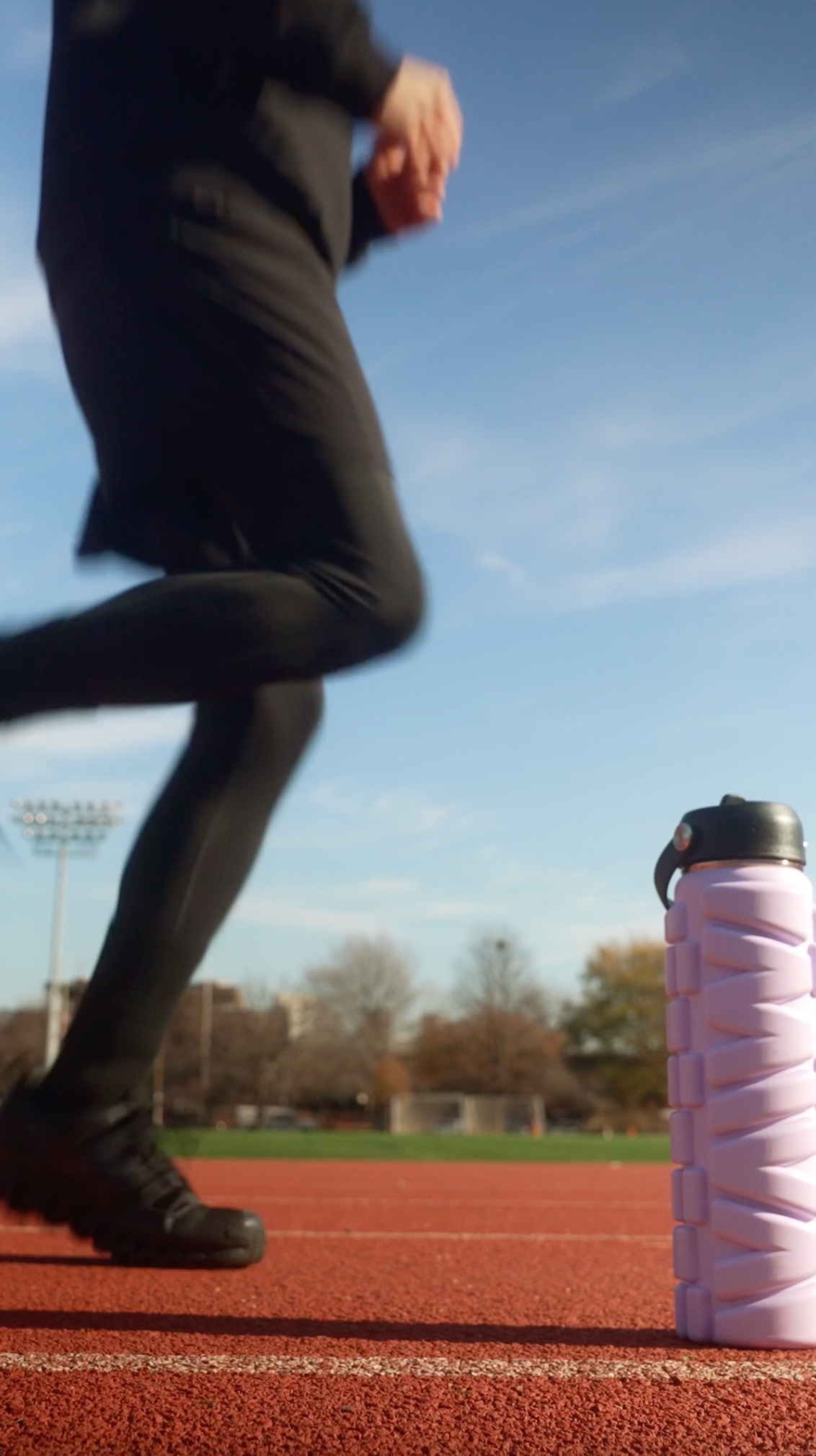 Model on a track using Lavender Haze 25 oz MIVA Recovery Foam Roller Water Bottle